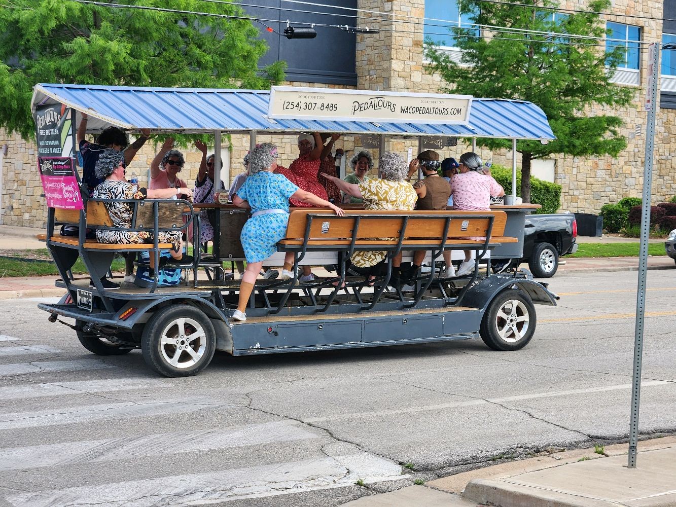 Group of riders pedaling the Waco Pedal Tours party bike during the day